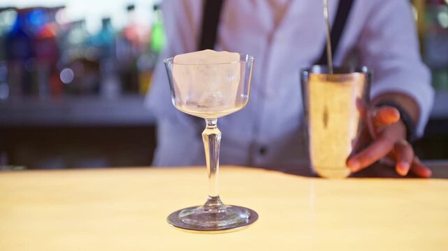 Professional bartender chilling cocktail glass with ice