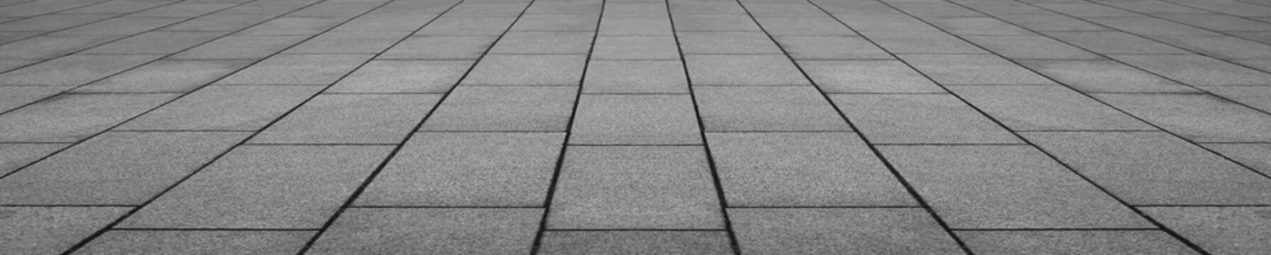 Abstract grey gray monochrome slabs stone floor pattern with geometric tile arrangement and perspective view creating a modern architectural surface in perspective view.