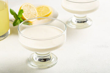 Creamy lemon posset dessert with limoncello served in elegant glass bowl on light background, fresh citrus dessert concept.