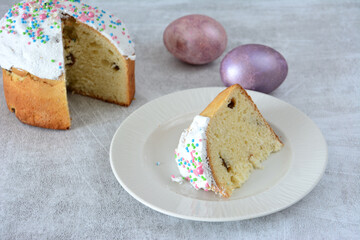 a slice of Traditional Easter Kulich with Icing, Sprinkles on a plate and Eggs copy space