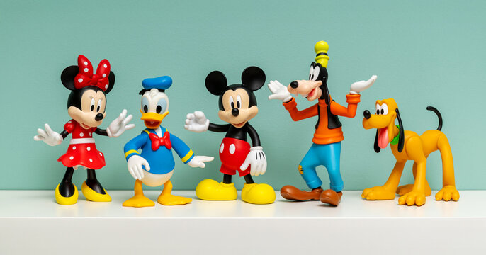 Walt Disney characters figurines standing on shelf against blue wall