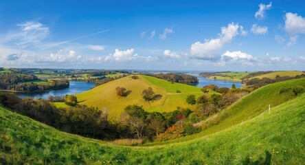Fototapeta premium Lush hillside panorama including grass fields, scattered trees, and natural water bodies