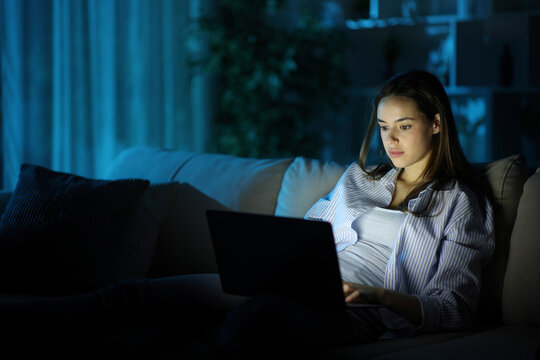Serious woman using personal computer in the night at home