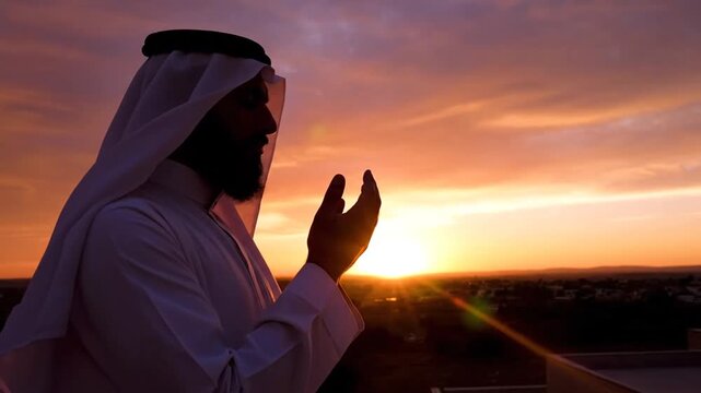 Muslim man praying at sunset standing on a rooftop in golden light