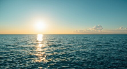 Obraz premium Beautiful sunlight shimmering over a calm blue ocean under a clear sky