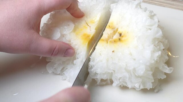 white crispy tremella mushrooms. In her hands is a knife, which she uses to slice clusters of tremella fuciformis on a plate. Cooking edible porcini mushrooms.