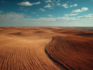 Fototapeta premium A wide view of a dry, rocky landscape under a bright blue sky with scattered clouds.