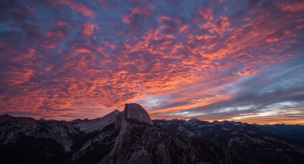 Fototapeta premium Beautiful twilight sky filled with glowing clouds above rugged mountain peaks at sunset