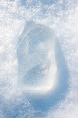 Ice block in the light blue tones on white fluffy snow background.