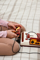 Retro gamepads in hand. Nostalgia for the 80s and 90s. Millennial leisure. Vertical orientation.