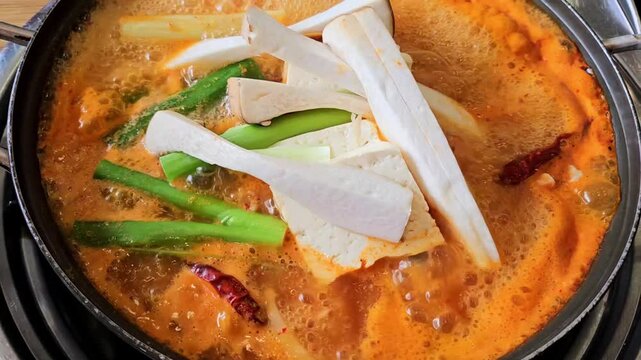 Close-up of boiling Korean spicy mushroom and tofu stew in a pot