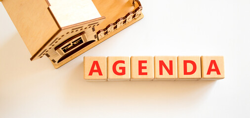 Fototapeta premium Agenda symbol. Concept word Agenda on beautiful wooden blocks. Beautiful white background. Beautiful wooden model of house. Business agenda concept. Copy space.