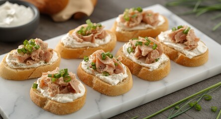 Delicate baguette slices topped with tuna cream cheese and fresh chives on a marble serving board