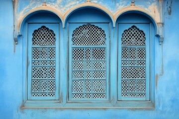 Obraz premium Blue wall with three ornamental arched windows and intricate golden latticework