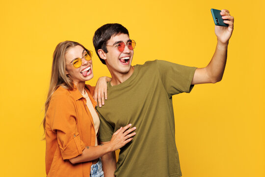 Young couple two friends family man woman wear casual clothes do selfie shot on mobile cell phone post photo on social network together isolated on pastel plain light yellow color background studio