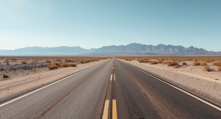 Asphalt desert street revealing rugged sand textures and distant mountain hills in summer light
