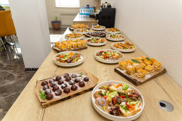 Assorted catering food with bruschetta, slider, and pastry on a wooden counter