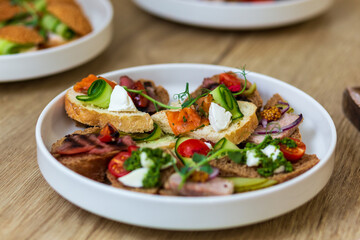 Close-up of a white plate with assorted gourmet canapes and mini sandwiches.