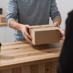 A person transfers a small brown box onto a wooden counter