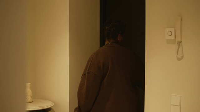 Tired African American woman with paper bags entering home, her husband working on laptop at dining table