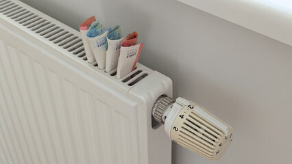 Euro cash on radiator frames turmoil around heating bills, turmoil spreads across Europe, high cost of living, recession fears, energy security campaigns.