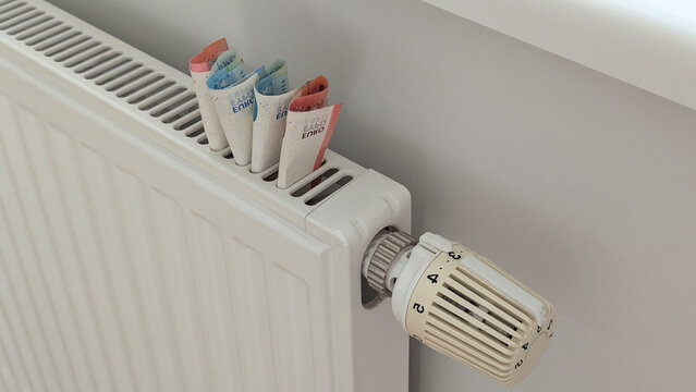 Euro cash on radiator frames turmoil around heating bills, turmoil spreads across Europe, high cost of living, recession fears, energy security campaigns.
