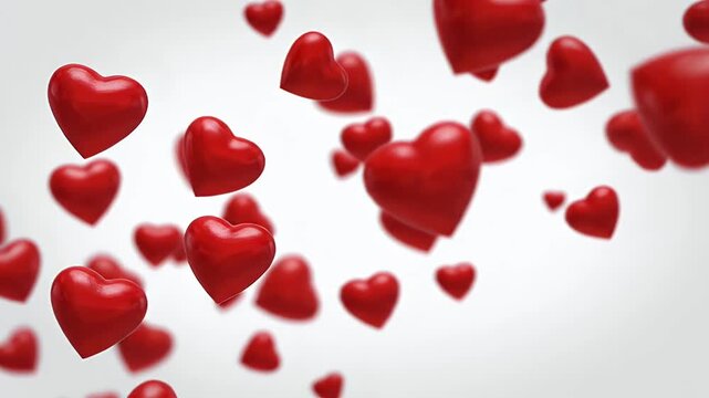 Red Hearts Floating on White Background - The video features multiple glossy red heart shapes of varying sizes, floating in a seemingly random pattern.