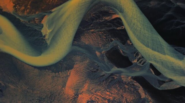 Aerial view of braided river tributaries weaving through a landscape of contrasting dark and light earth tones, Selfoss, Iceland.