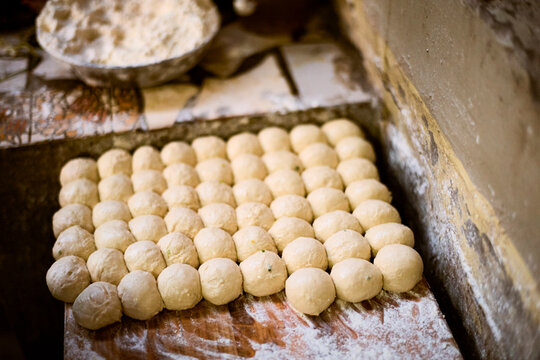 Dough balls arranged neatly on a flour-dusted wooden surface ready for baking. Kigali, Rwanda