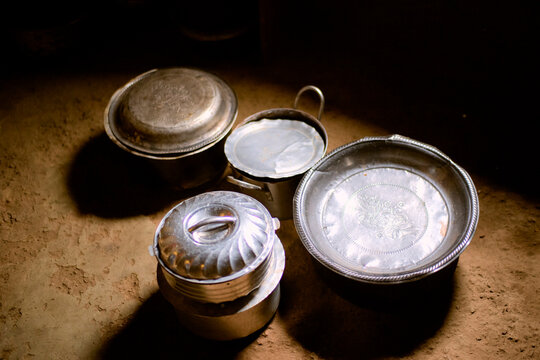 Four rustic metal cookware items sit on a textured brown surface in soft lighting. Kigali, Rwanda
