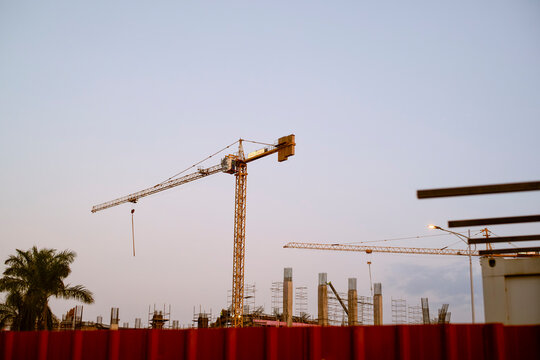 Construction site with cranes and palm tree at sunset under a clear sky. Kigali, Rwanda