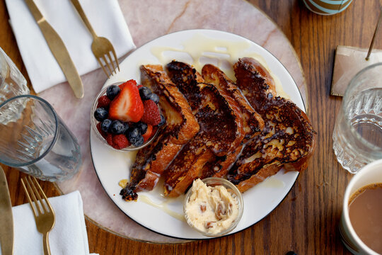 French toast with syrup, fresh berries, and butter on a wooden table setup. Miami, Florida, USA