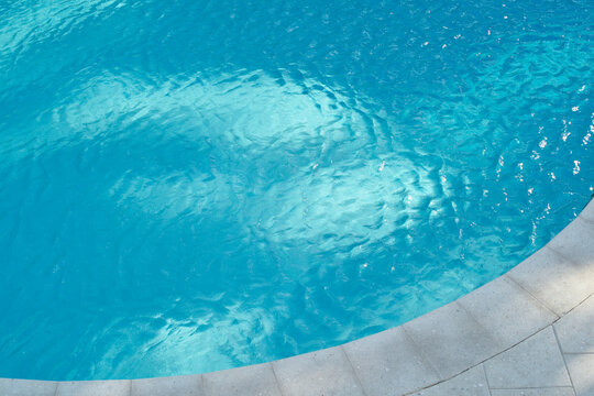 Clear blue pool water with a curved stone edge under sunlight. Miami, Florida, USA