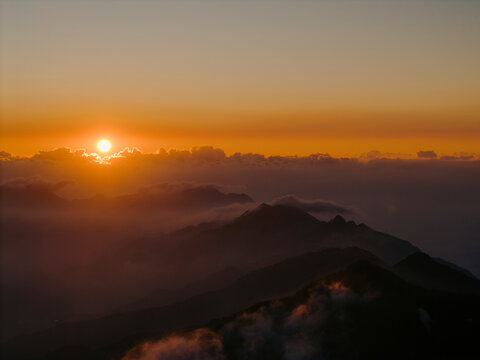 Sunrise casting warm light over misty mountains and valleys in serene landscape. Ta Xua, Bac Yen District, Son La, Vietnam