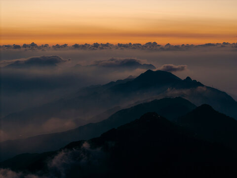 Majestic mountain peaks emerge from misty clouds at sunset, creating a serene landscape. Ta Xua, Bac Yen District, Son La, Vietnam
