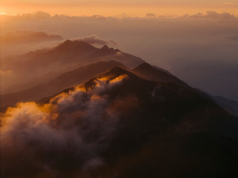 Mountain range silhouetted against a vibrant sunset with clouds enveloping peaks. Ta Xua, Bac Yen District, Son La, Vietnam
