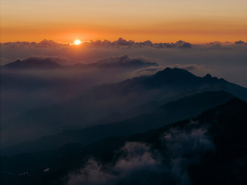 Sunset over a mountain range with clouds and mist creating a dramatic landscape. Ta Xua, Bac Yen District, Son La, Vietnam