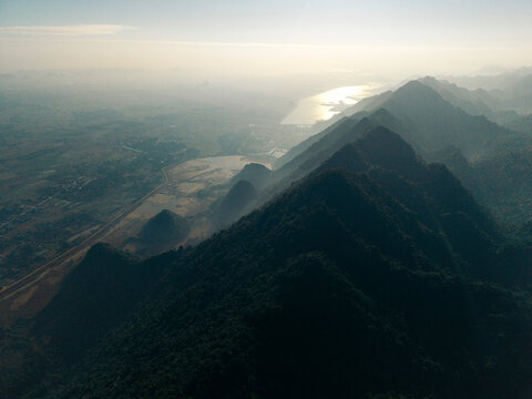 Aerial view of a mountain range with valley and river at sunrise creating a misty atmosphere. Yen Thuy District, Hoa Binh, Vietnam