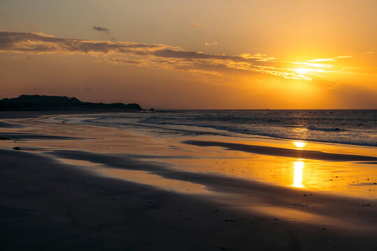 Golden sun setting over a tranquil beach, with waves gently lapping at the shore. Zhouzi Bay, Taiwan, New Taipei City, Tamsui District