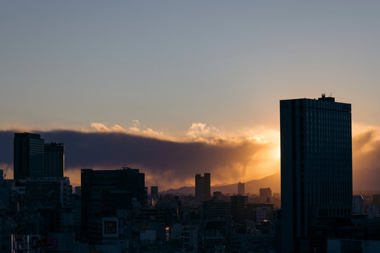 City skyline silhouetted against a golden sunset with dramatic cloud formations. Tokyo, Japan