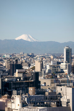 City skyline against a mountain backdrop with clear blue sky and urban buildings. Tokyo, Japan