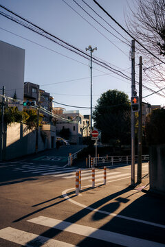 Quiet urban street corner with a pedestrian crossing and distant buildings at sunrise. Tokyo, Japan