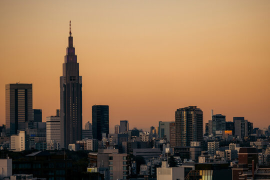 City skyline with tall buildings silhouetted against a warm sunset sky. Tokyo, Japan