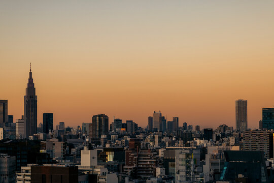 City skyline at sunset with silhouetted buildings and a warm gradient sky. Tokyo, Japan