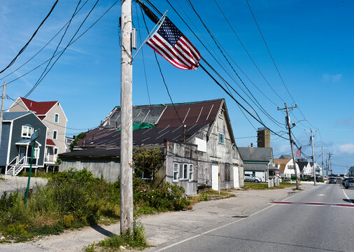 Weathered building on a street with an American flag under a clear blue sky. Marshfield, USA