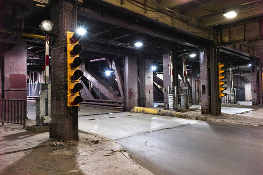 Dimly lit urban underpass with industrial beams and multiple traffic signals. Chicago, Illinois, USA