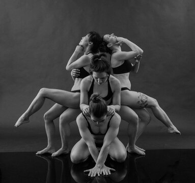 Four dancers in intricate poses creating a dramatic, artistic scene in black and white. WA, USA