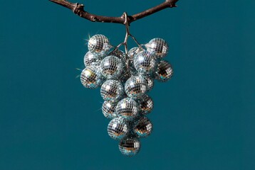 Fototapeta premium Creative food art of a grape bunch with mirror disco ball grapes on teal background