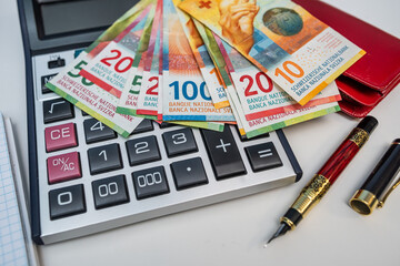 Swiss Franc Banknotes with Calculator and Wallets for Personal Finance and Global Banking Concept