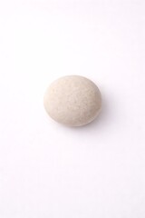 Single round light-colored smooth natural stone on white seamless background with copy space